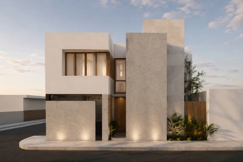Fachada principal de la casa patio al atardecer: volúmenes blancos y de travertino con iluminación rasante.